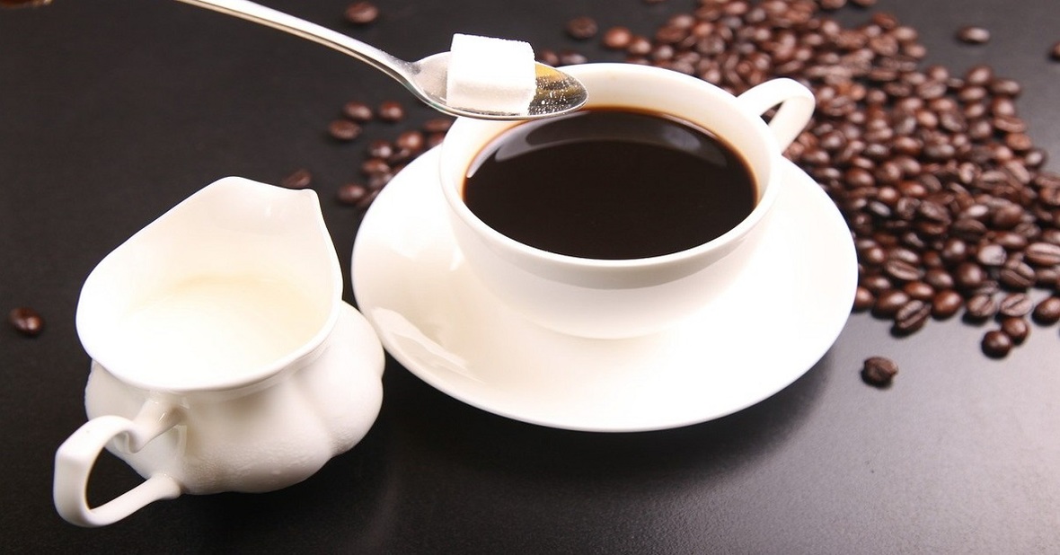 Persona añadiendo un terrón de azúcar a una taza de café, algo no recomendable al preparar comidas para personas mayores