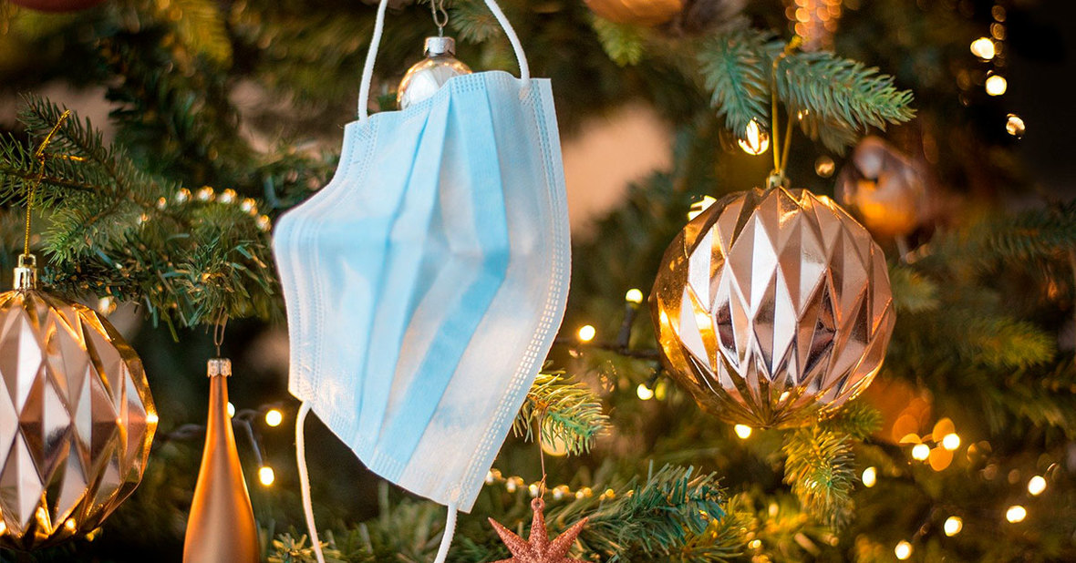 Mascarilla colgando en un árbol de Navidad al lado de otros adornos, un símbolo de unas fiestas navideñas seguras frente al coronavirus
