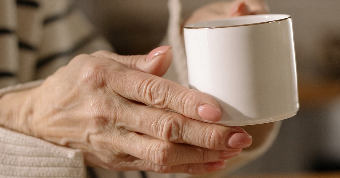 Manos de una mujer mayor sujetando una taza de café