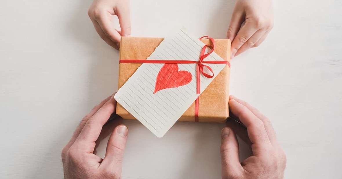 Nieto dándole a su abuelo un regalo envuelto y con una tarjeta con un corazón dibujado