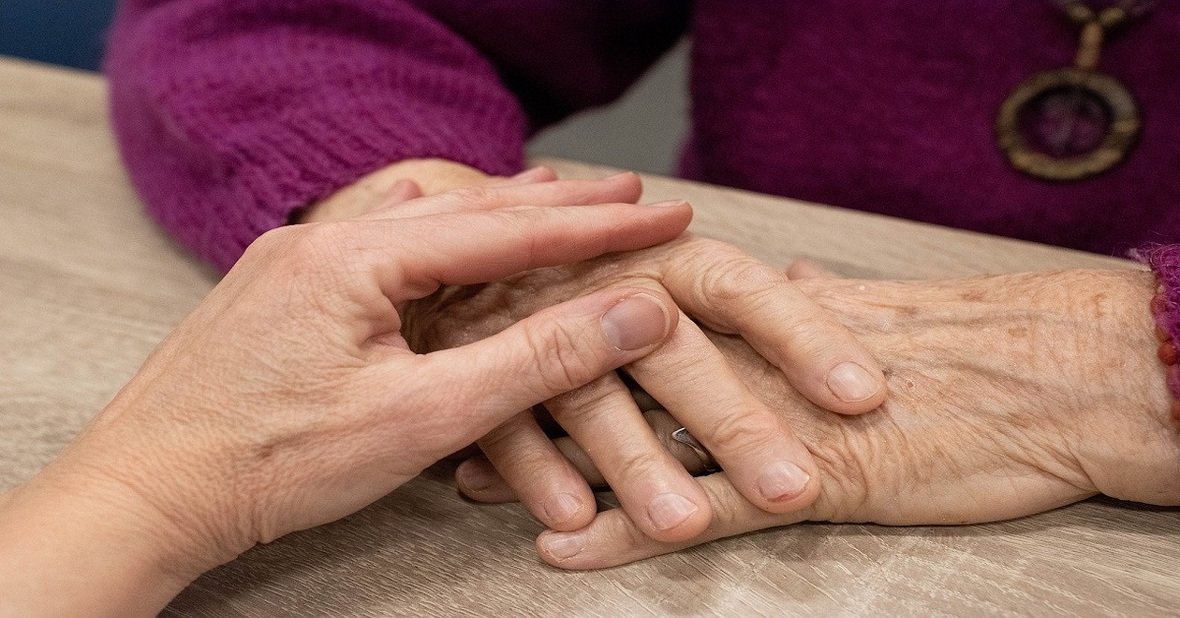 Cuidador acariciando las manos de la persona mayor que sufre de agitación nocturna