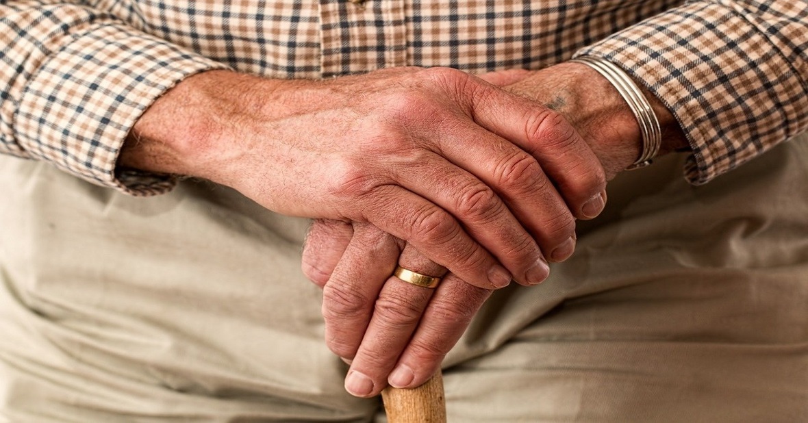 Manos de persona mayor sosteniendo un bastón porque padece de artritis o artrosis