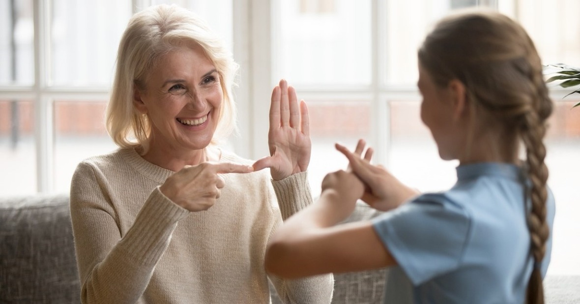 Mujer mayor hablando lenguaje de signos con una niña, una forma de comunicarse con personas con sordera