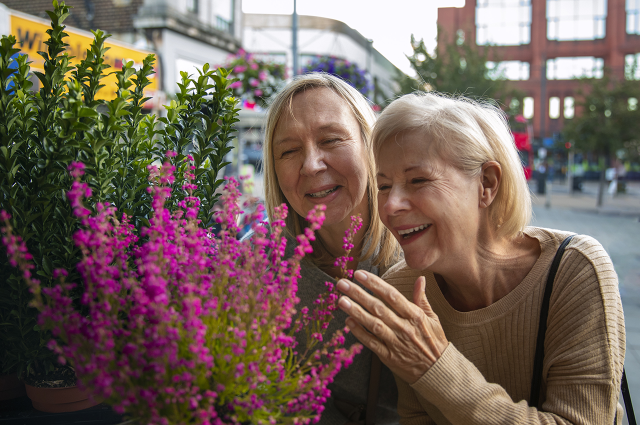 Dos mujeres mayores sonrientes mientras ver unas flores.