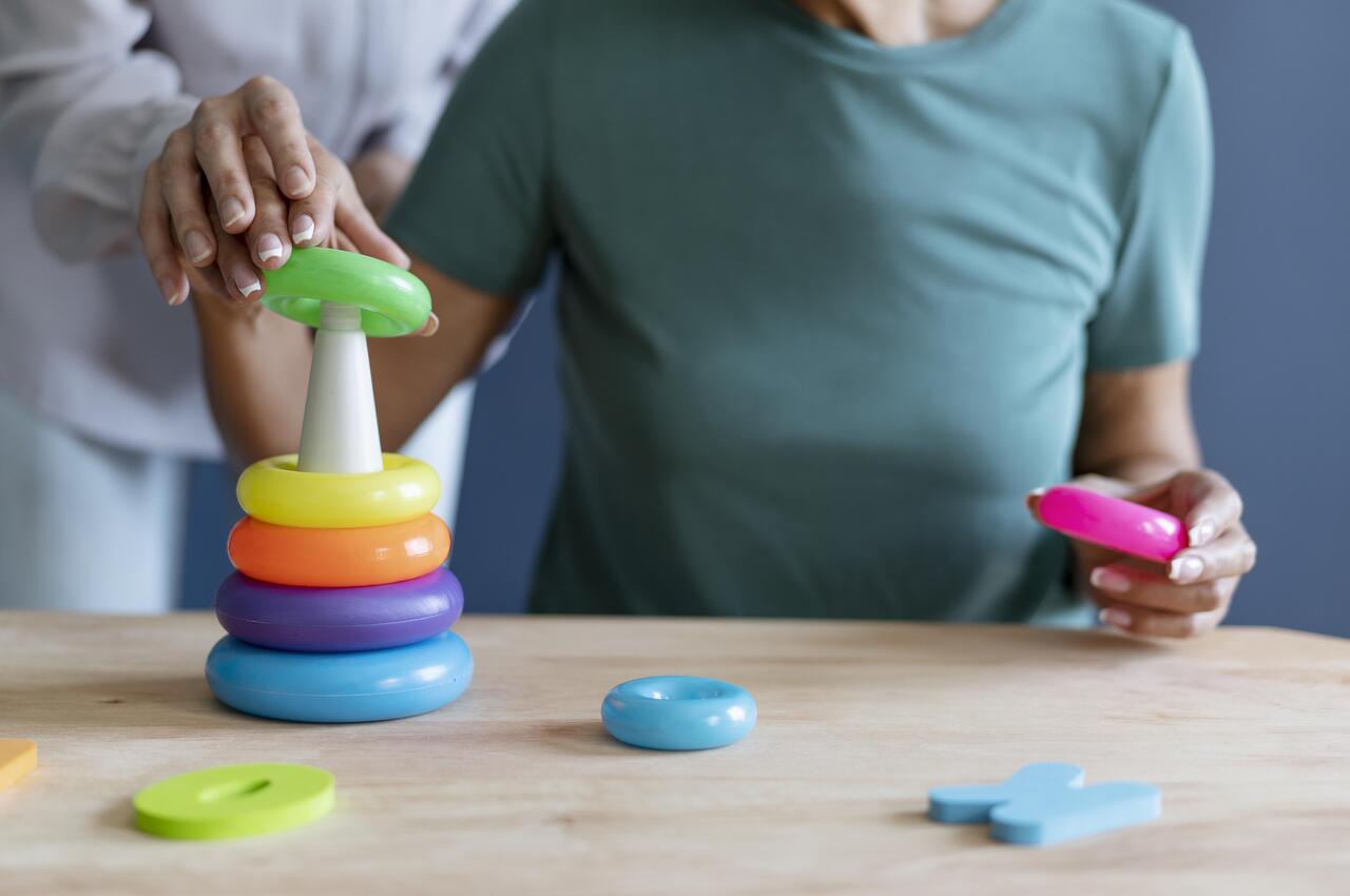 Una mujer mayor haciendo ejercicios de estimulación psicomotriz en una sesión de terapia ocupacional.