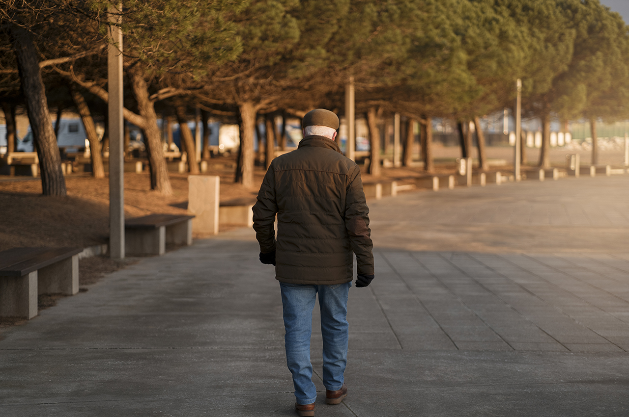 Un hombre mayor de espaldas, bien abrigado, dando un paseo.