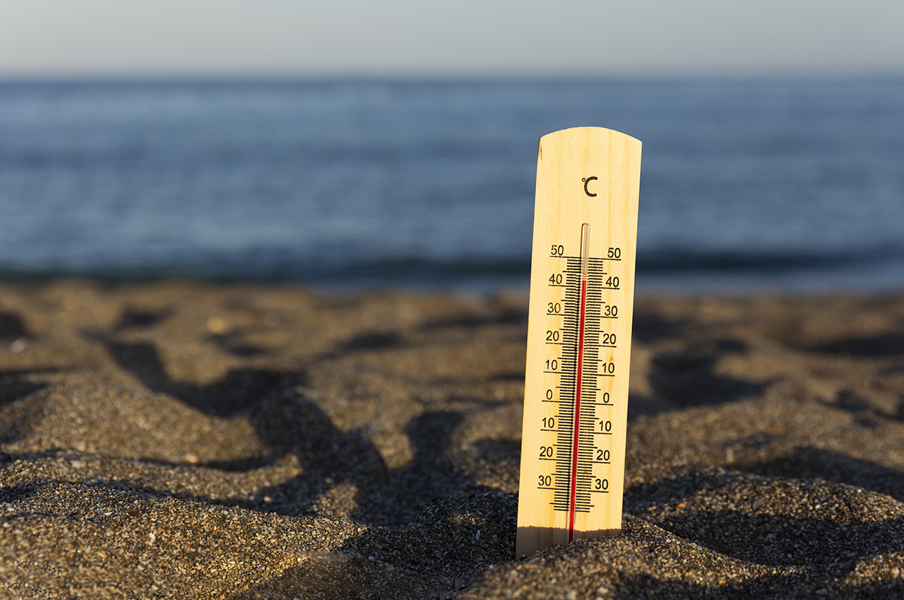 Un termómetro clavado en la arena de una playa marca altas temperaturas.