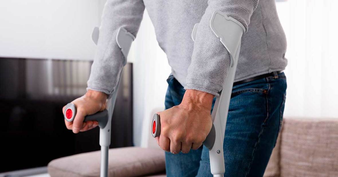 Persona mayor con movilidad reducida usando muletas para moverse y evitar las escaras de presión
