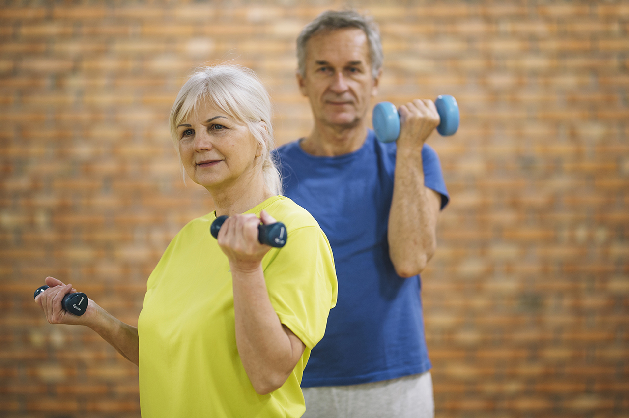 Una mujer y un hombre mayor haciendo ejercicio con mancuernas