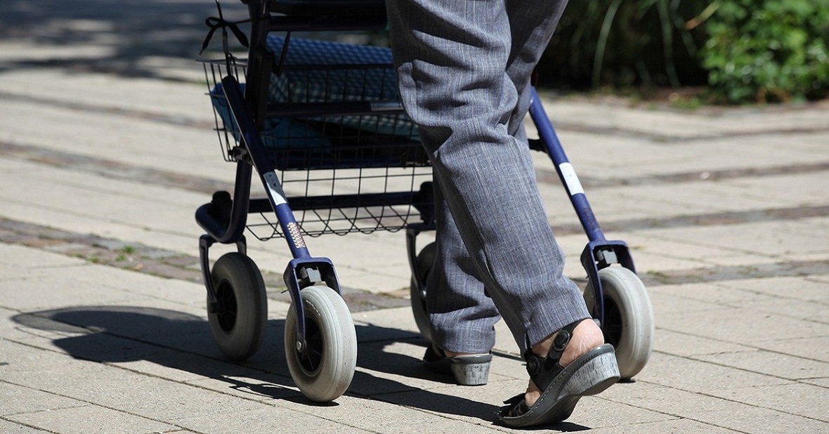Hombre mayor utilizando un andador para moverse porque le duelen las piernas