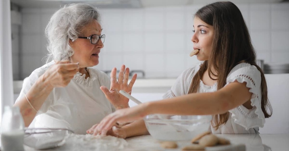 Nieta comiéndose una galleta mientras cocina con su abuela