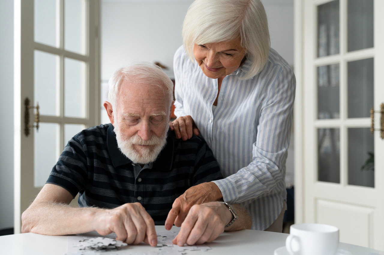 Hombre mayor haciendo un puzzle acompañado de una mujer mayor