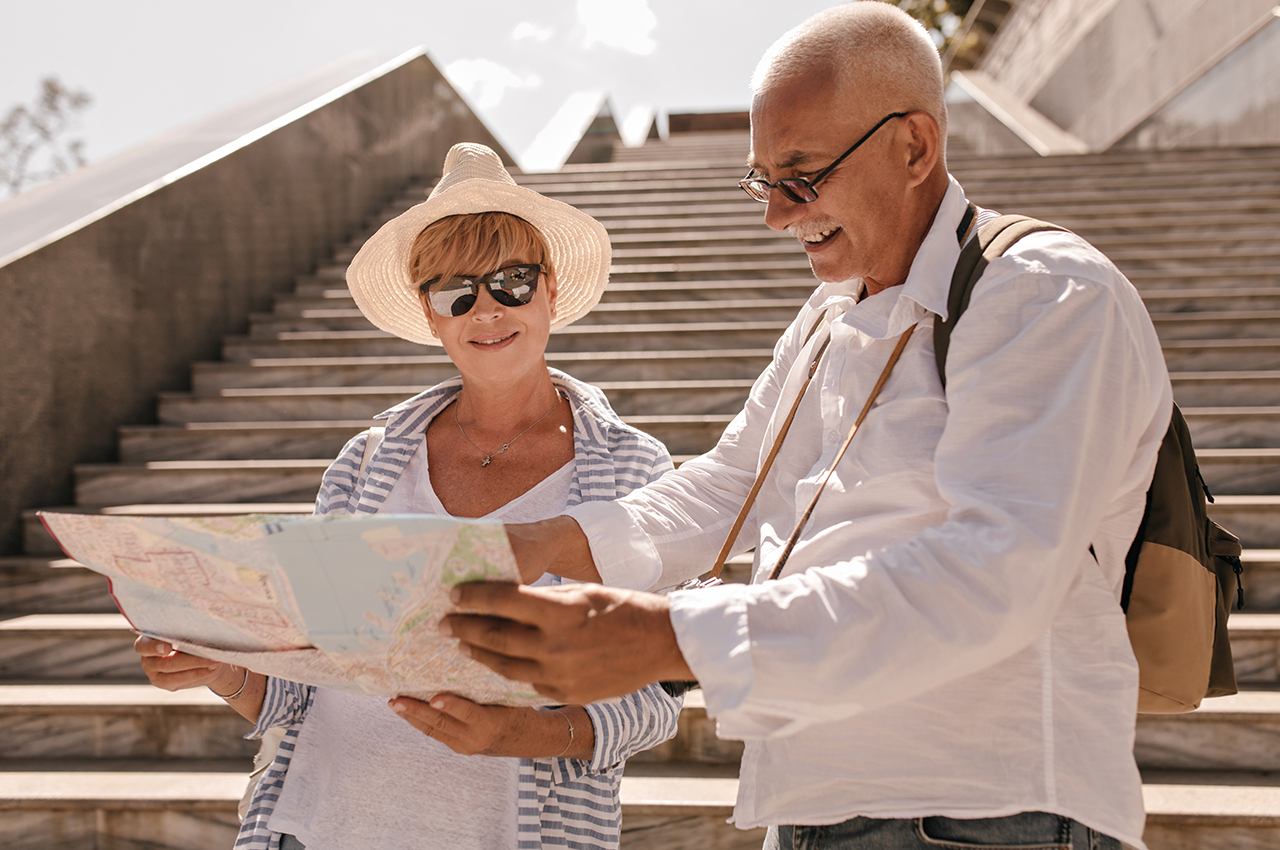 Un hombre mayor y una mujer de mediana edad miran un mapa de la ciudad que están visitando.