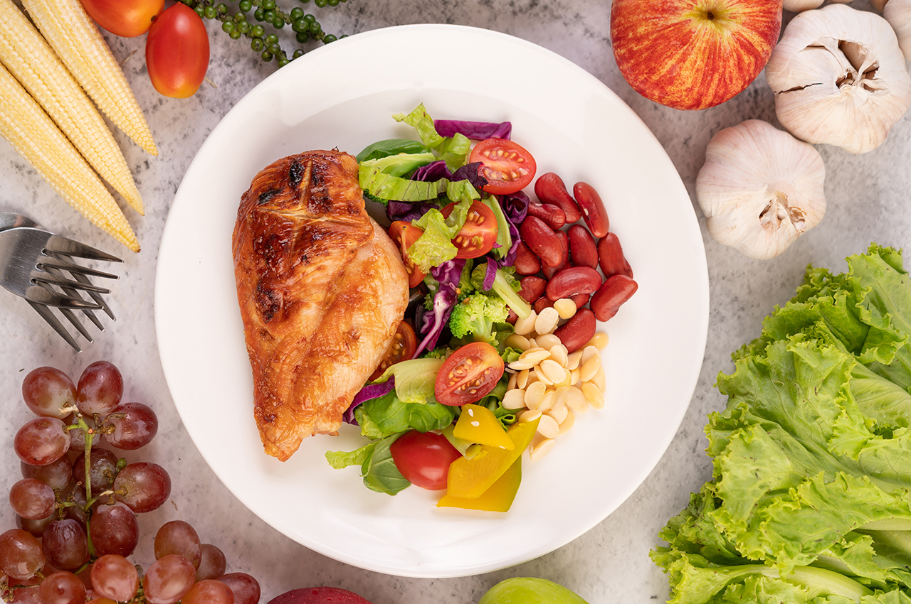 Un plato con pollo al horno y verduras de acompañamiento.