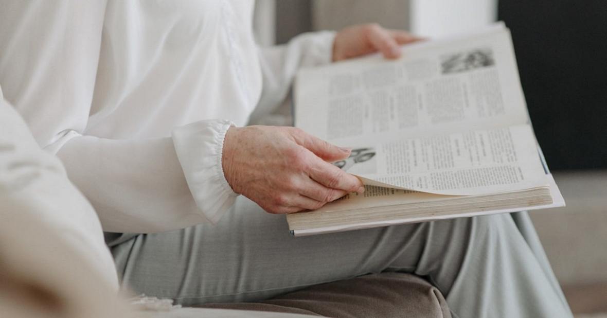Mujer mayor leyendo un libro mientras está en casa