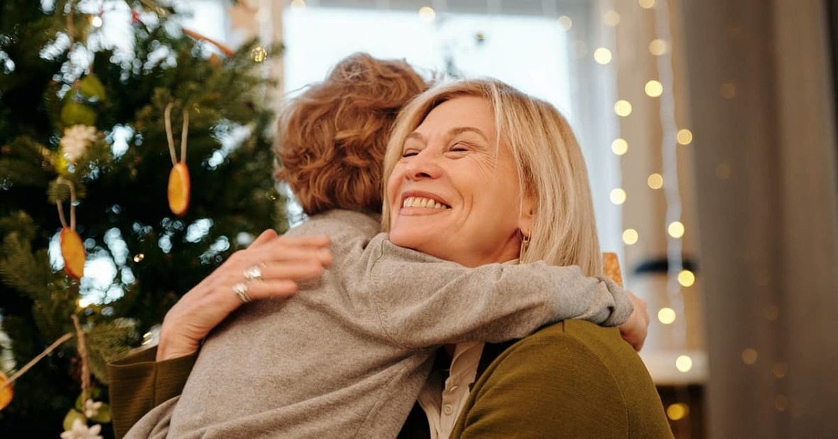 Abuela abrazando a su nieto con decorado navideño de fondo