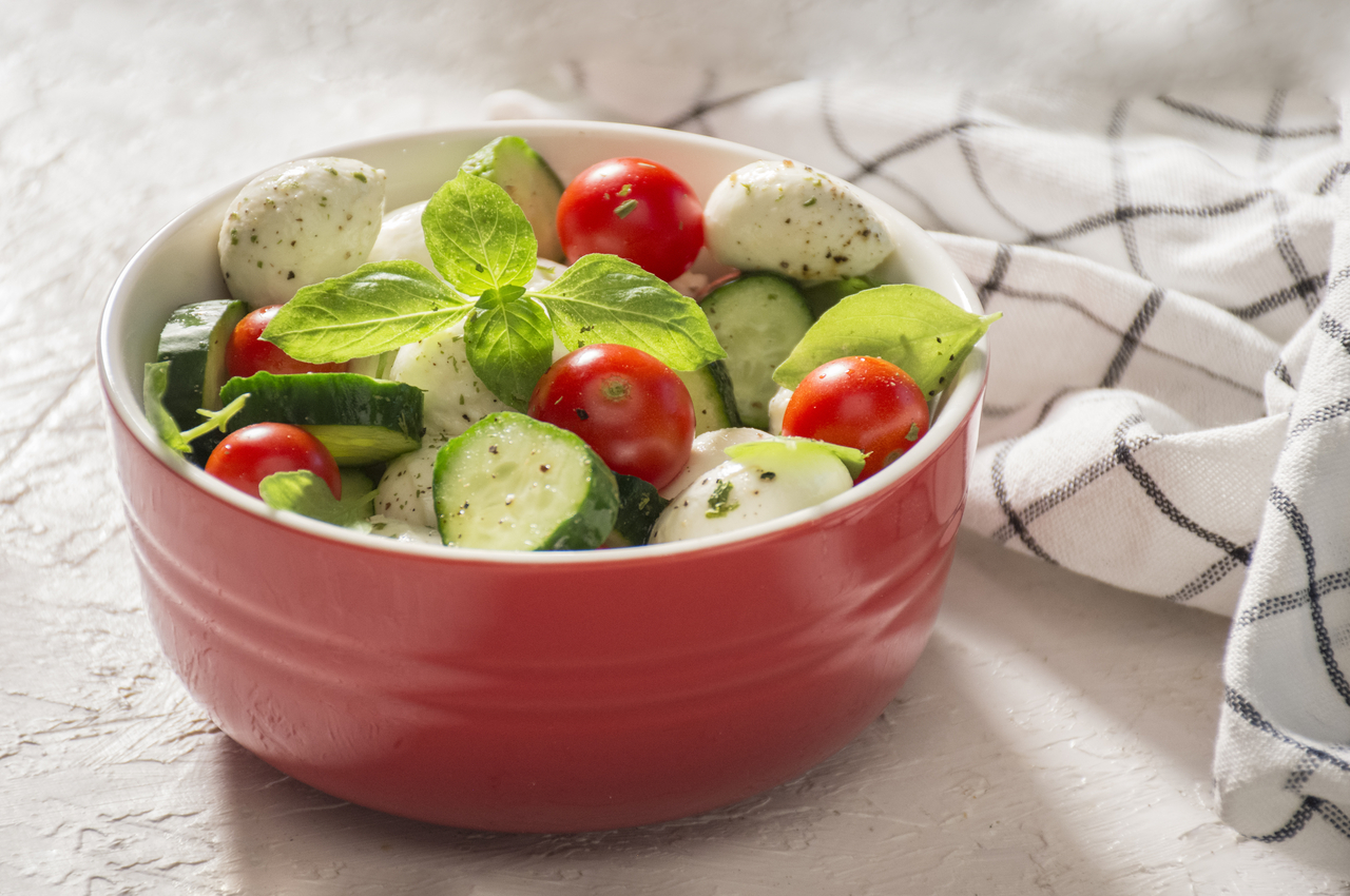 Una ensalada con queso feta, tomate y pepino.