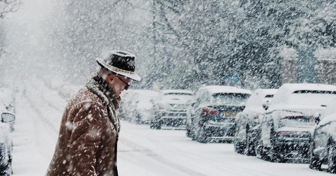 Hombre mayor cruzando la calle durante una tormenta de nieve