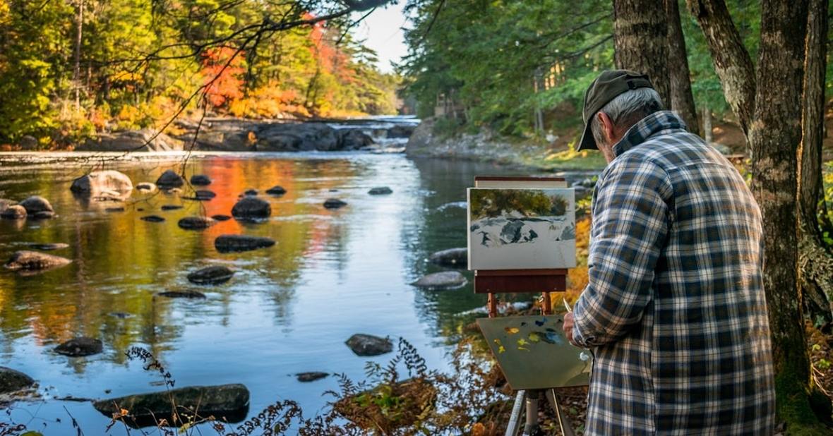 Hombre mayor pintando en un lienzo un paisaje en Canadá, una actividad artística que ayuda a la estimulación cognitiva