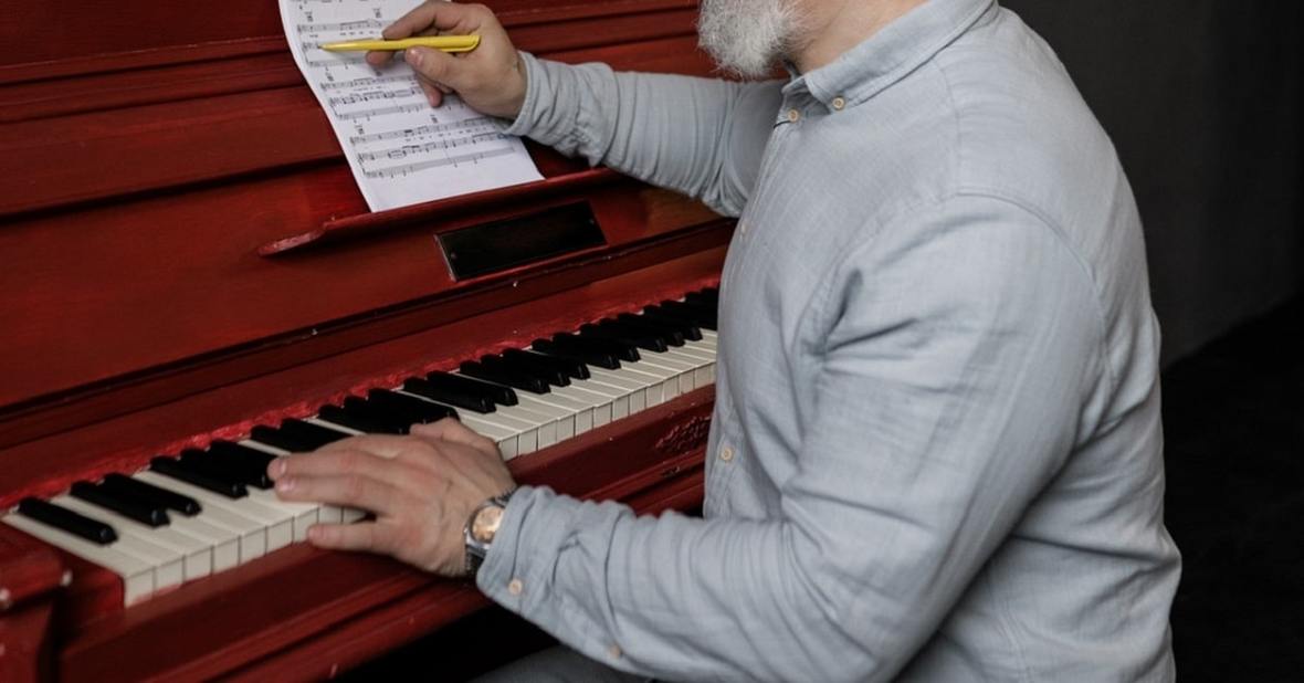 Persona escribiendo en una partitura sentado al piano