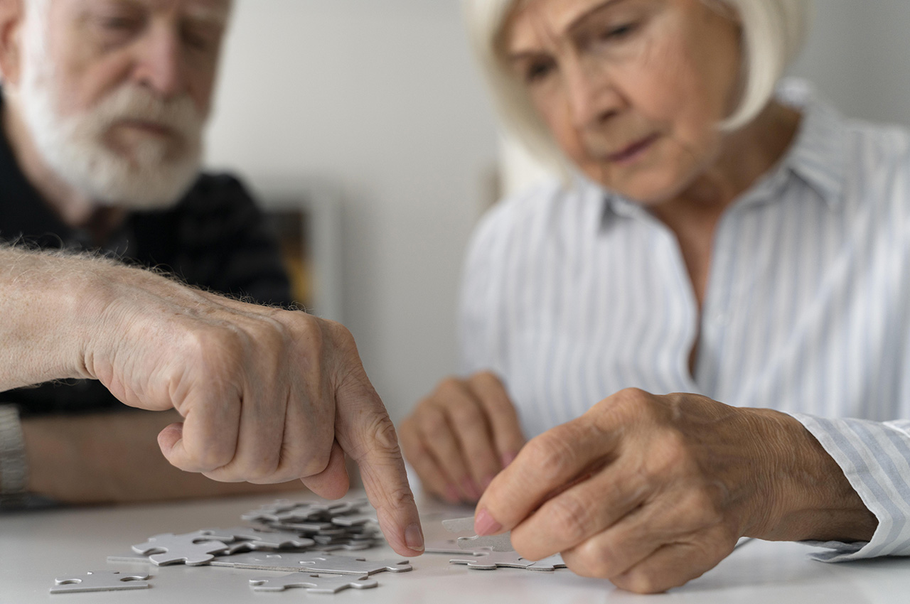 Una pareja de personas mayores haciendo un puzle.
