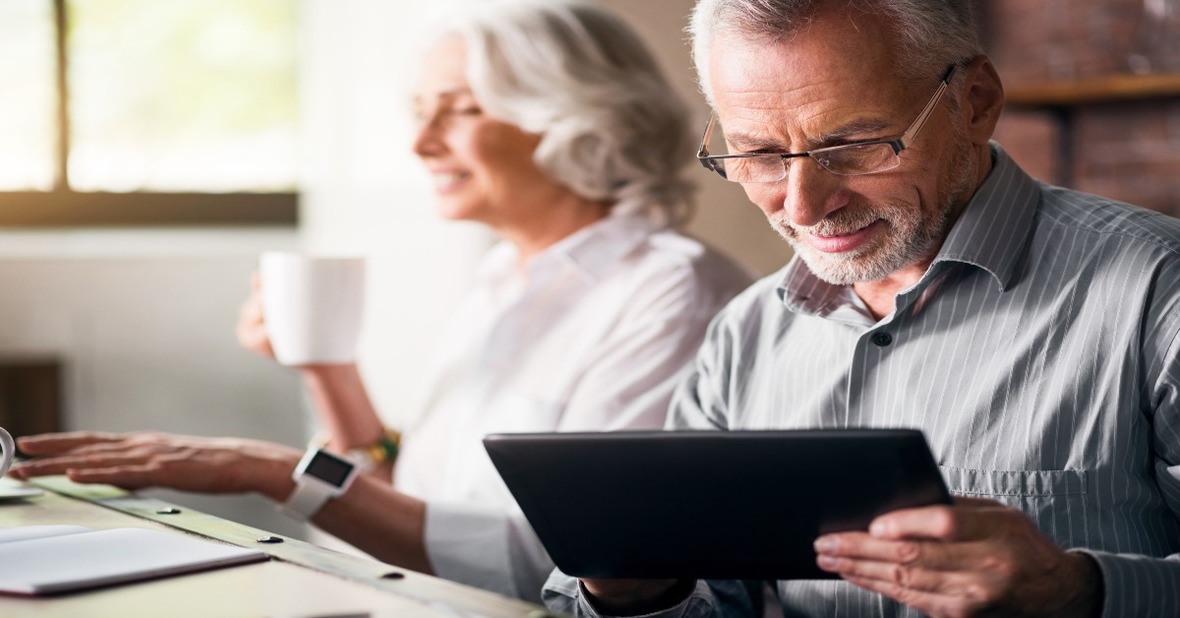 2.	Dos personas mayores con distintas edades y capacidad, una tomando un café y otra utilizando un dispositivo digital, una tablet