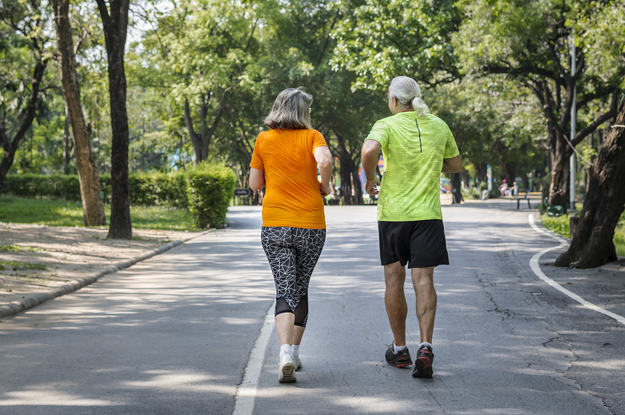 Una mujer y un hombre mayor caminan con ropa deportiva.