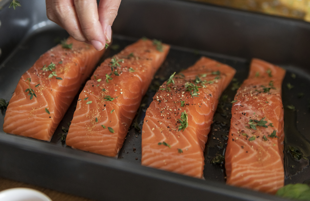 Filetes de salmón salpimentados en una bandeja a punto de ser cocinados al horno.