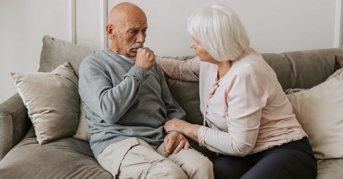 Mujer mayor ayudando a su pareja, un hombre mayor con disfagia, durante un ataque de tos