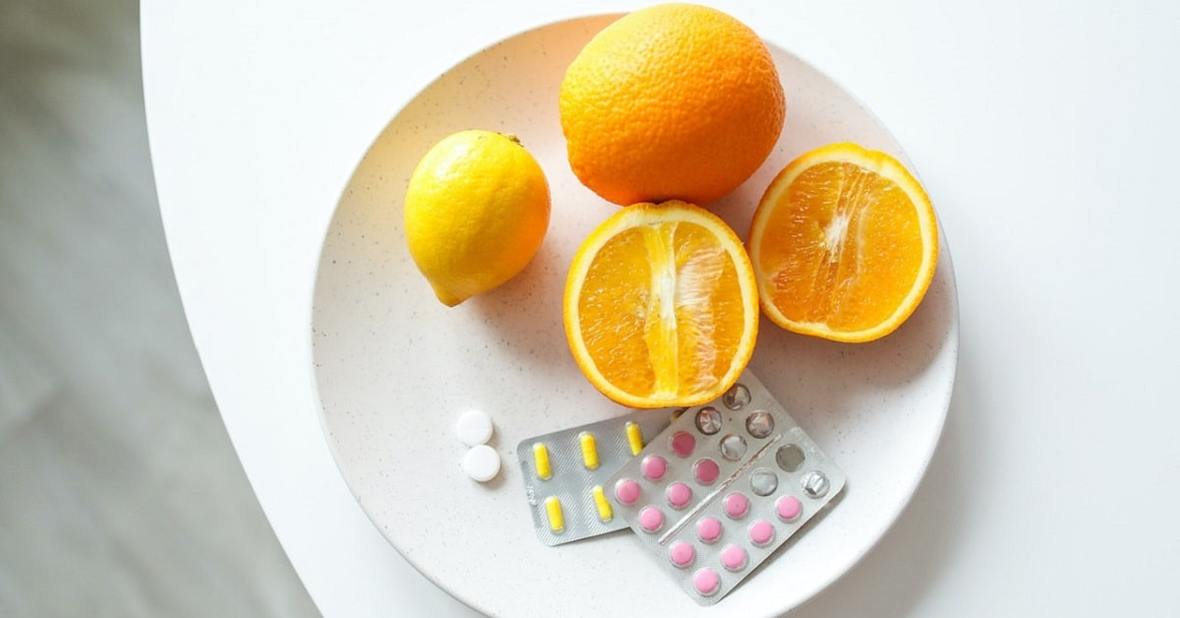 Plato con naranjas y varios blíster de suplementos vitamínicos