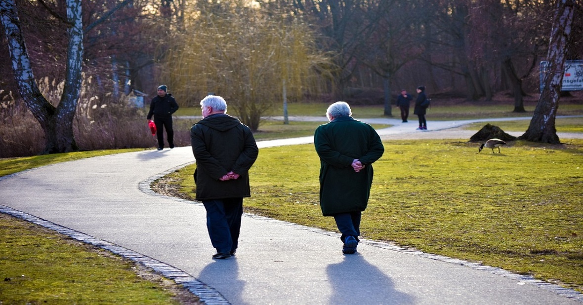 Dos personas mayores paseando por un parque, un buen hábito para conseguir un envejecimiento activo
