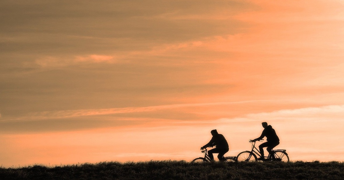 Dos personas montando en bicicleta, una actividad física recomendada para adultos mayores