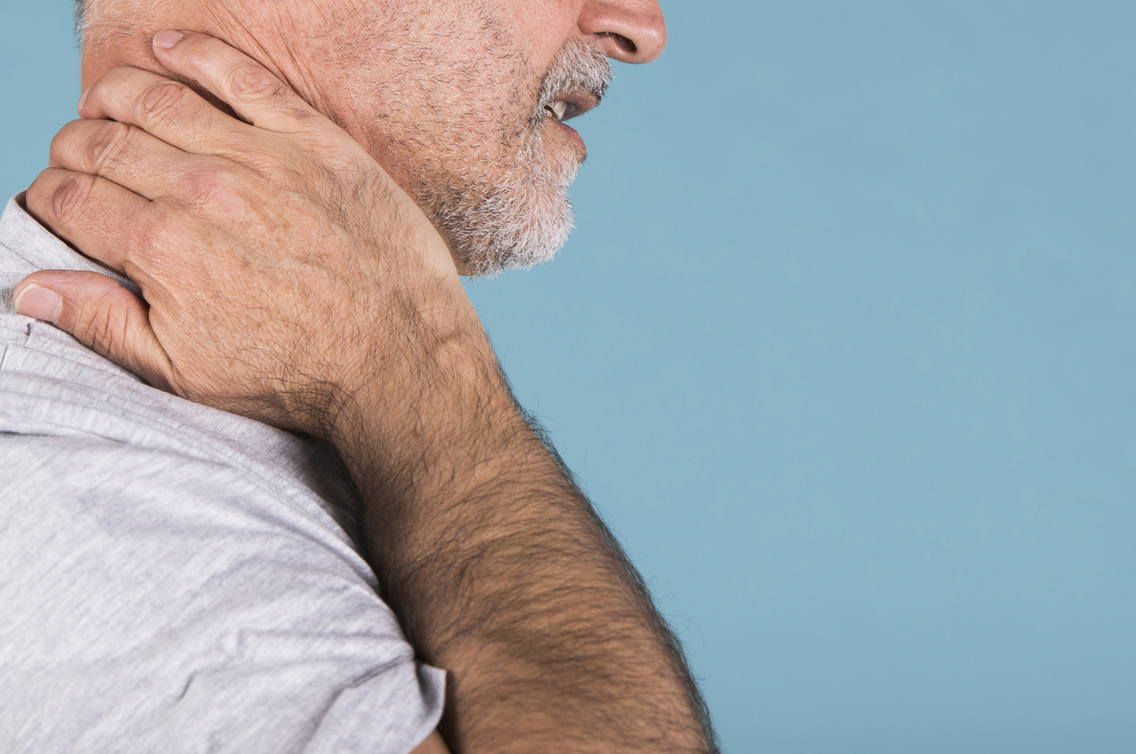 Un hombre se lleva la mano al cuello, dolorido.