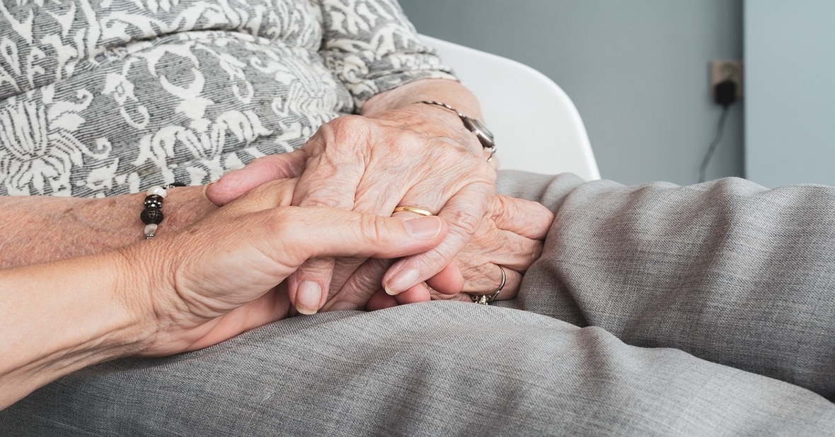 Cuidador sosteniendo las manos de una anciana, una forma de cómo tratar a una persona mayor