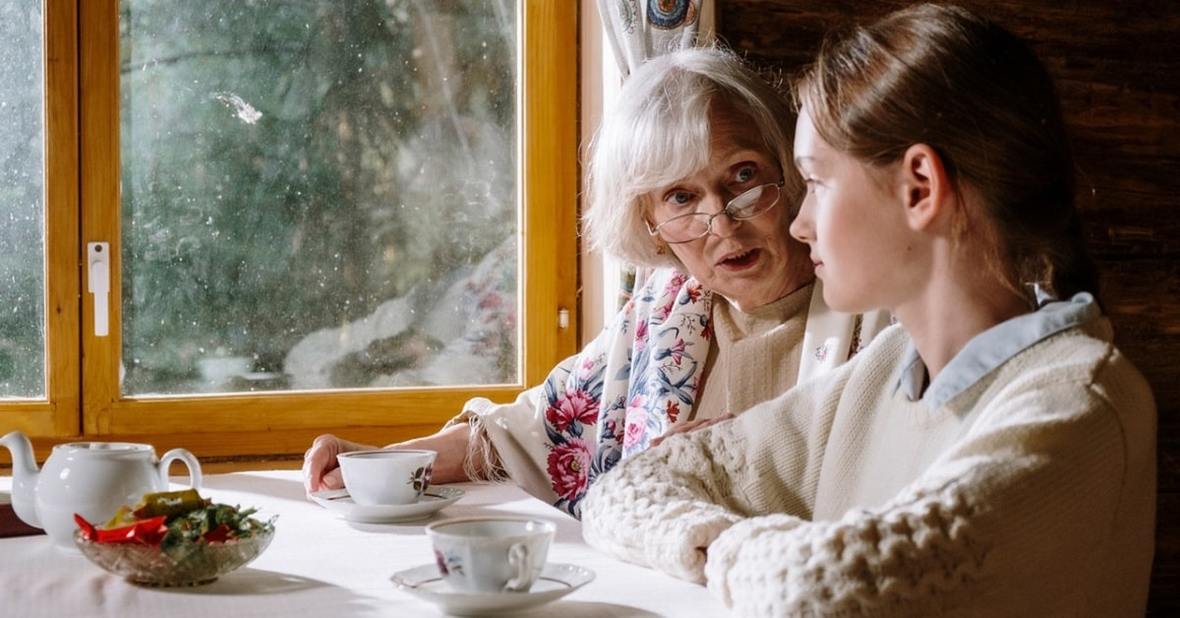 Abuela conversando con su nietas, sentadas en la mesa del comedor
