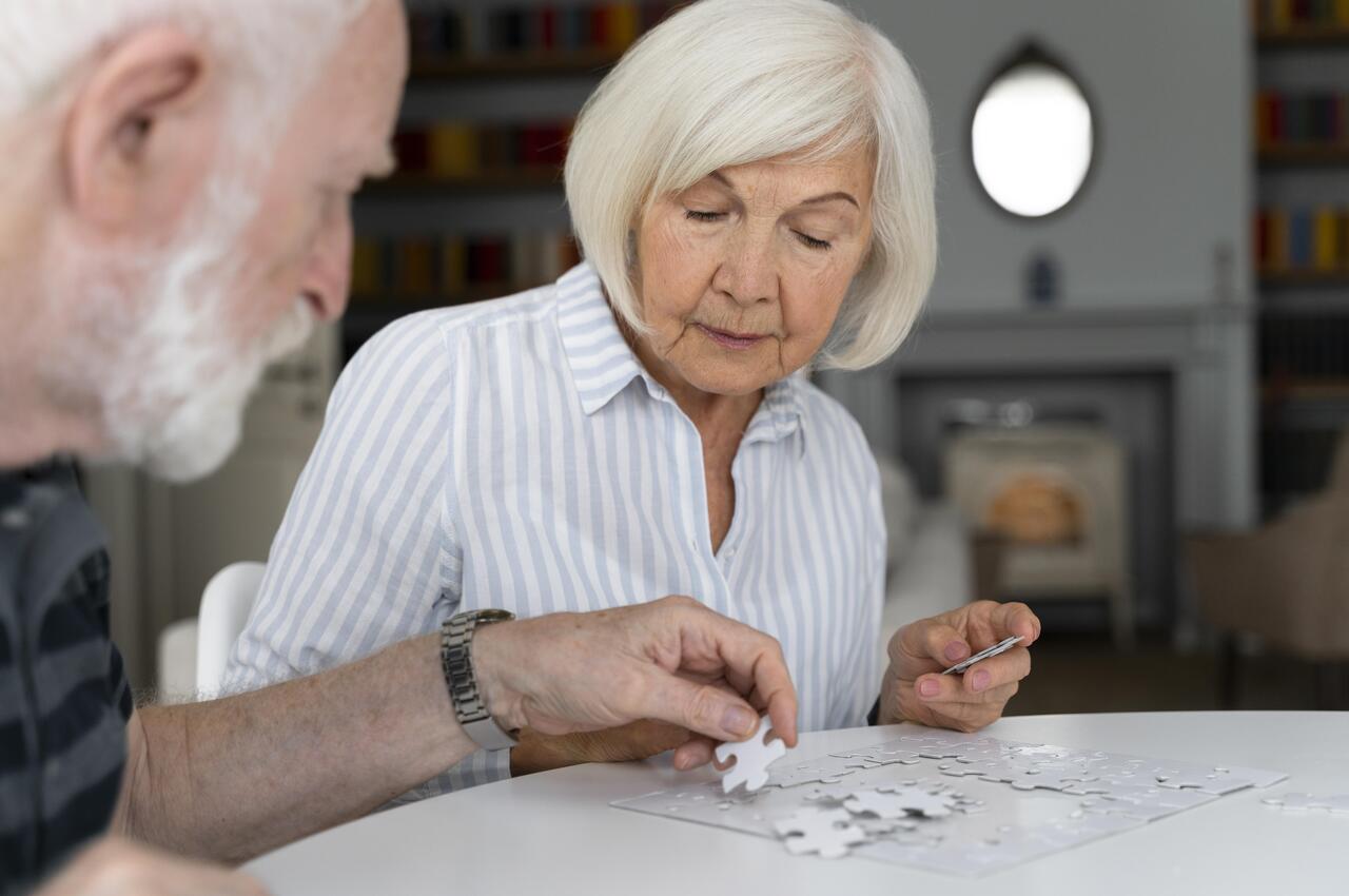 Mujer mayor haciendo un puzle junto a su marido.