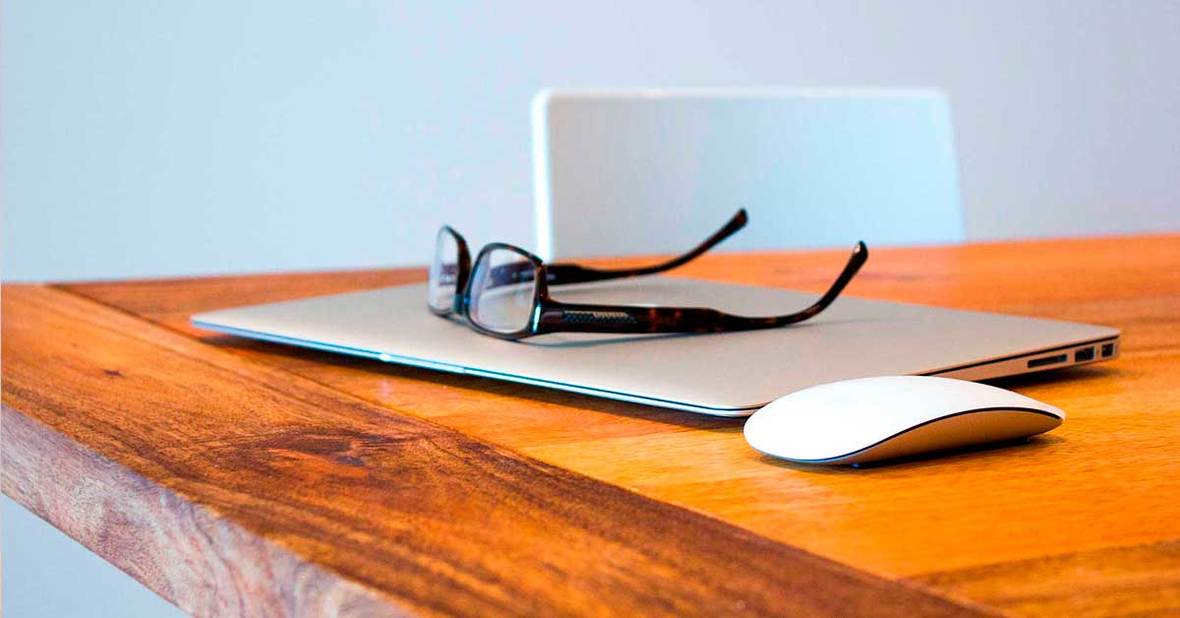 Ordenador portátil con unas gafas encima colocado sobre una mesa, un medio para informarnos sobre cómo cuidar a un anciano