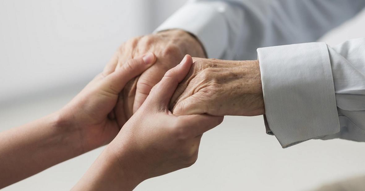 Persona agarrando las manos de un adulto mayor con artrosis