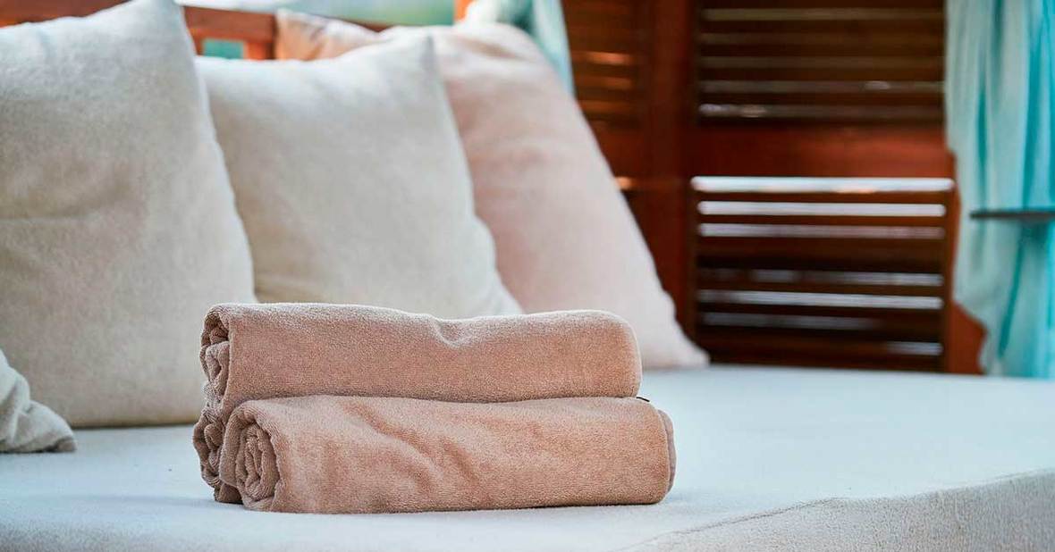 Cama de una persona dependiente encamada con las sábanas limpias recién puestas y unas toallas limpias encima