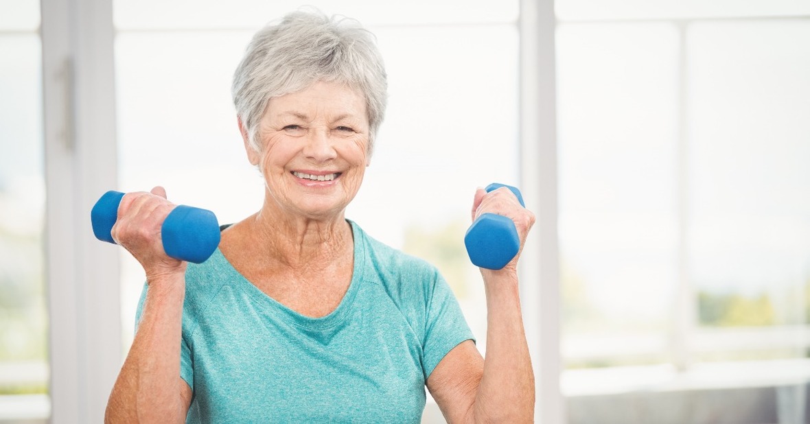 Mujer mayor levantando pesas, un ejercicio de gimnasia para mayores sentados que sirve para fortalecer los brazos