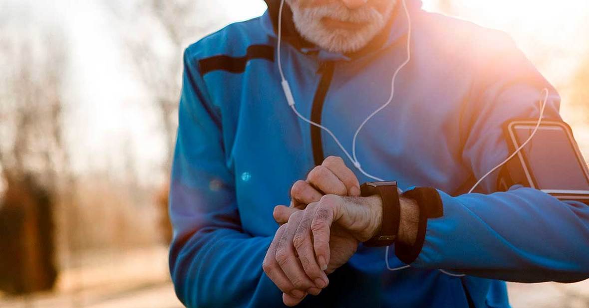 Hombre mayor corriendo con ropa de deporte y una pulsera de los servicios de teleasistencia en Andalucía
