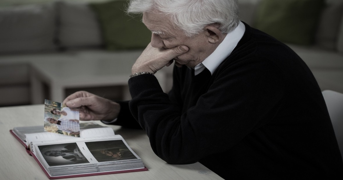 Hombre mayor viudo mirando un álbum de fotos con nostalgia, factor que pude provocar depresión en la tercera edad