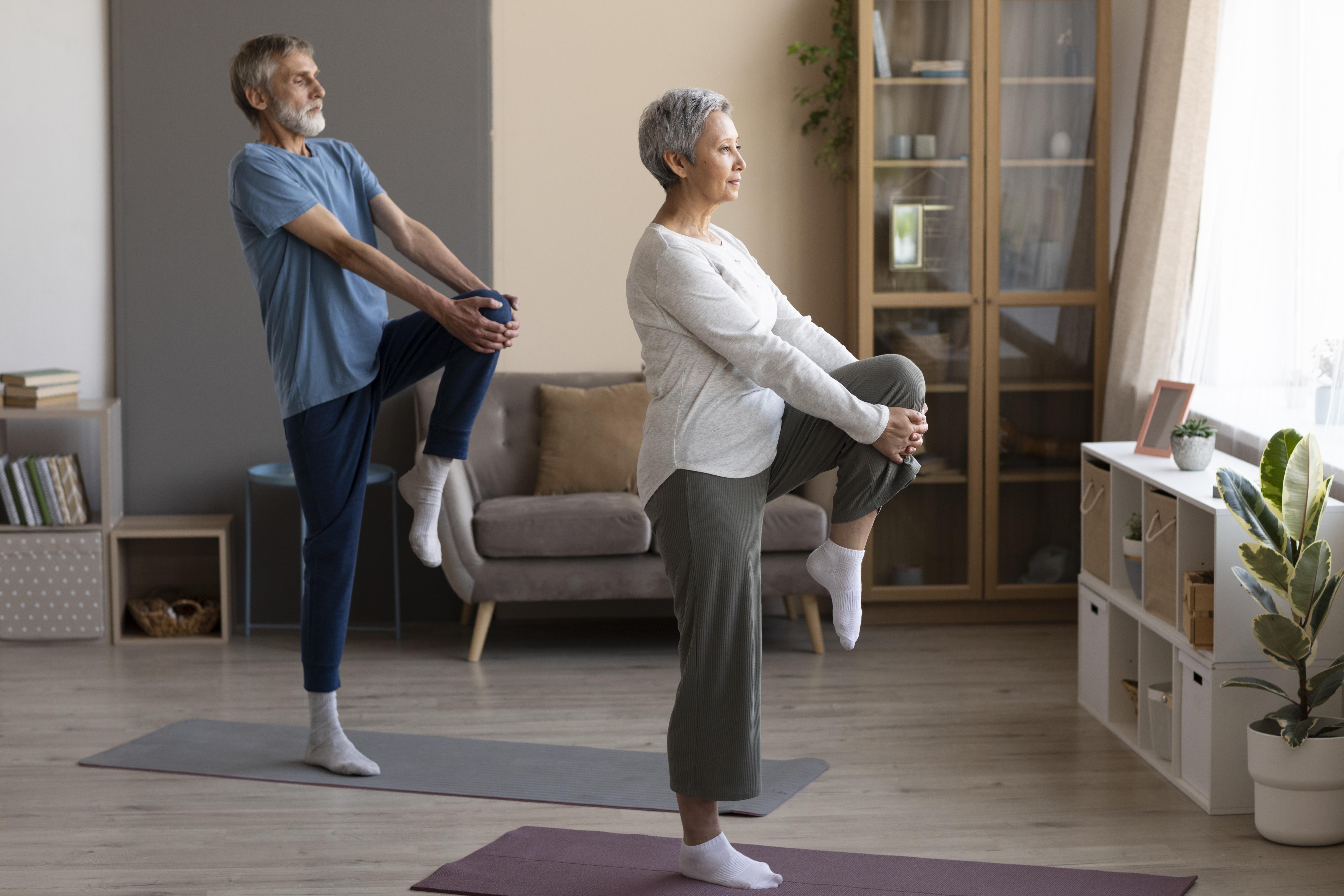 Una mujer y un hombre mayores haciendo ejercicios de equilibrio sobre esterillas.