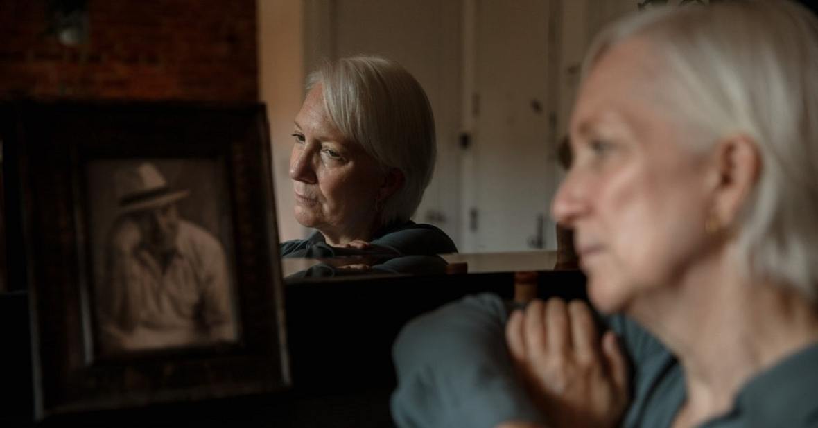 Mujer mayor mirando un marco con la foto de su marido fallecido
